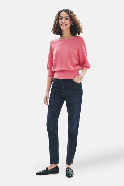Pull à col rond rose de Caroll, porté avec un jean foncé et des mocassins noirs avec chaînes dorées.
