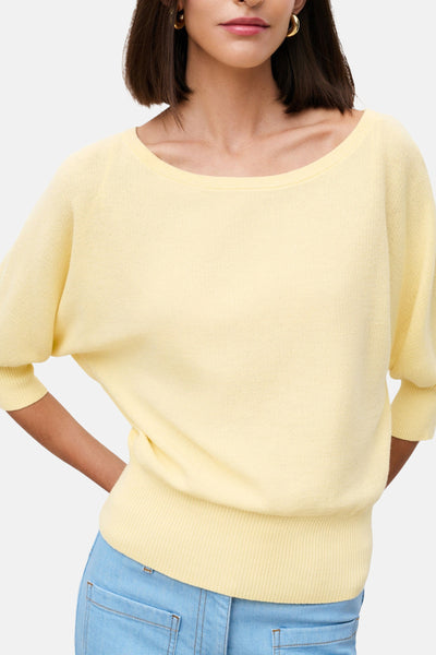 Pull jaune col O de CAROLL en maille fine avec manches 3/4 amples et poignets côtelés, porté avec un jean bleu clair.