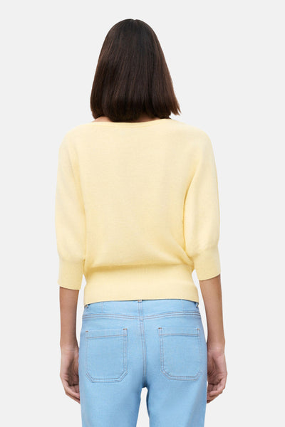 Pull jaune à col rond de CAROLL en maille fine à manches courtes, porté de dos avec un jean clair.