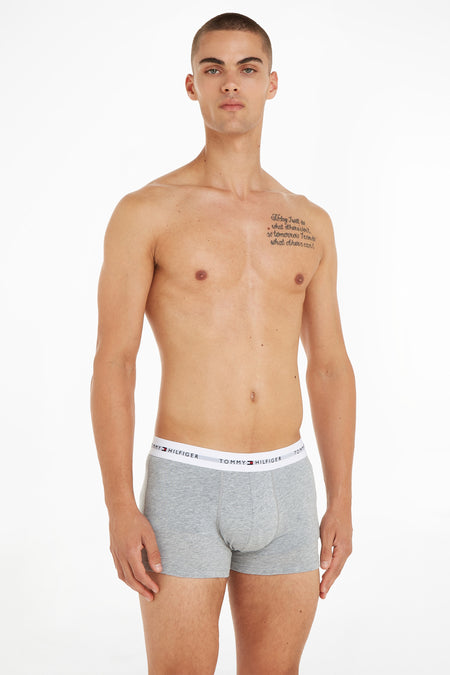 Zwarte boxer van Tommy Jeans met wit, gelogotapeerd band, gedragen door een man zonder bovenkleding.