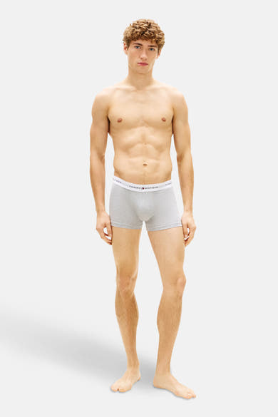 Boxer gris de Tommy Jeans, porté par un homme torse nu et musclé, debout devant un fond blanc.