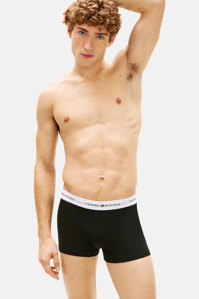 Boxer noir par Tommy Jeans avec ceinture blanche logotypée, porté par un homme torse nu.
