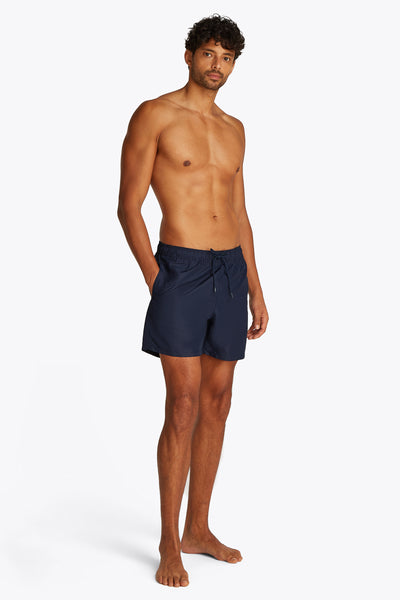Short de bain bleu marine de TOMMY HILFIGER, porté par un homme torse nu.