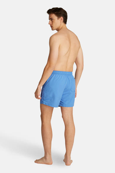 Blauwe zwembroek van TOMMY HILFIGER, met een achterzak en een halflange pasvorm, gedragen door een man van achteren gezien.