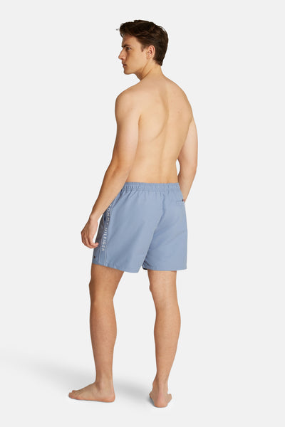 Blauwe zwembroek van TOMMY HILFIGER, met logo op de zijkant en een naakte man.