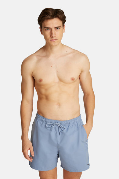 Blauwe zwembroek van TOMMY HILFIGER, gedragen door een man zonder shirt.
