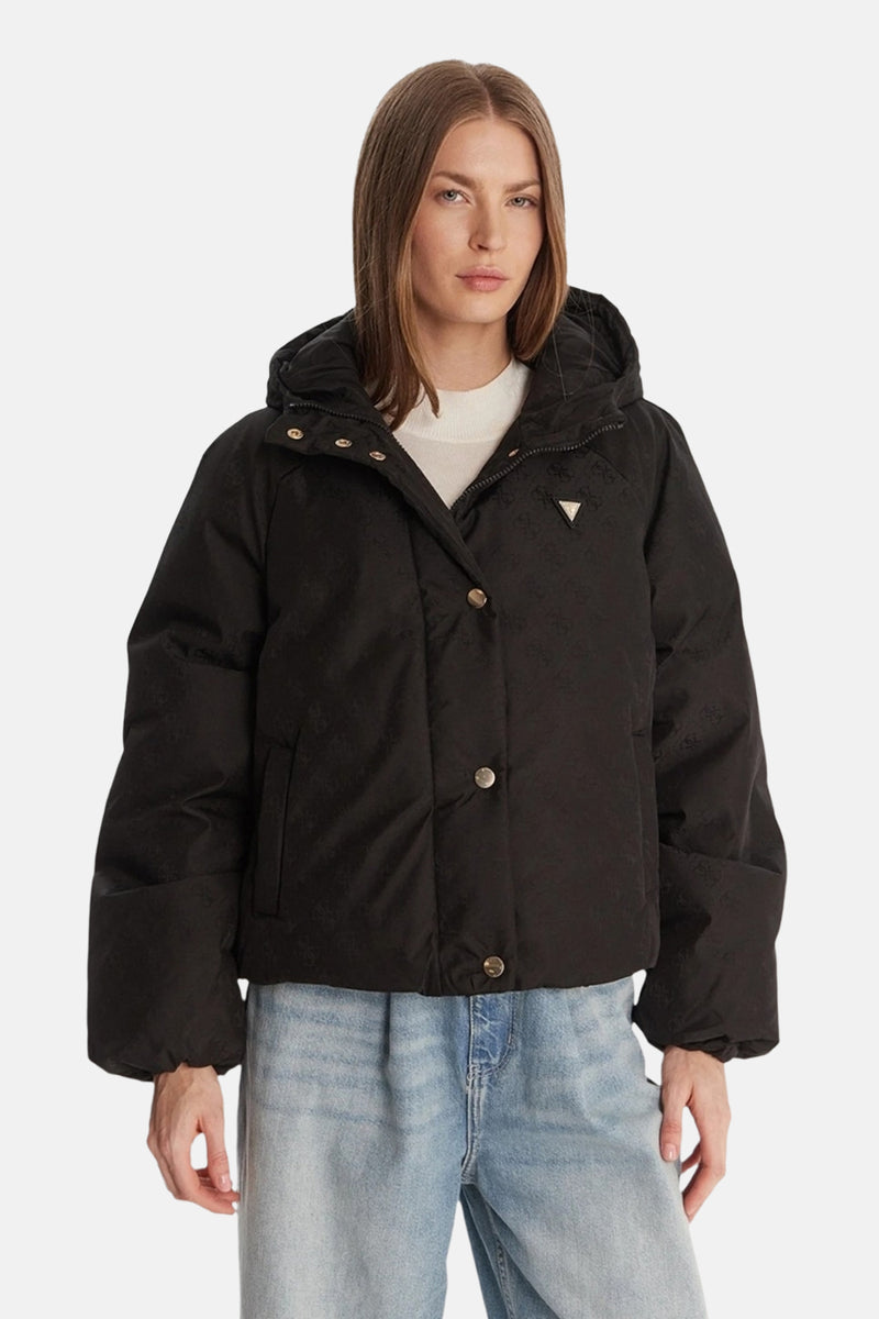 Veste courte noire de Guess, avec une capuche et des boutons dorés, portée sur un pull blanc et un jean bleu clair.
