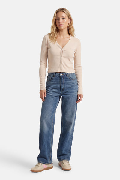 T-shirt écru à manches courtes de Guess, porté avec un cardigan et un jean larges.
