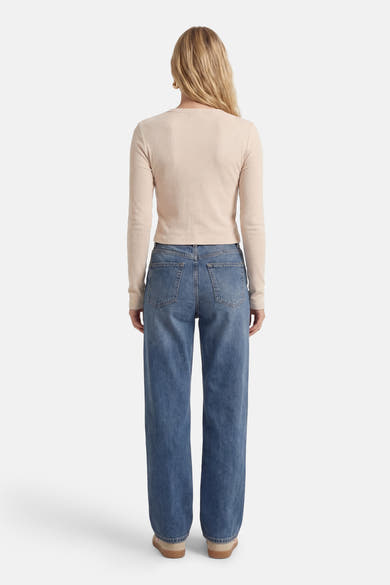Ecru T-shirt met korte mouwen van Guess, gedragen met een wijde blauwe jeans en beige platte schoenen, achterzicht.