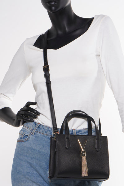 Zwarte VALENTINO BAGS schoudertas met dunne schouderriem en gouden details, gedragen door een model.