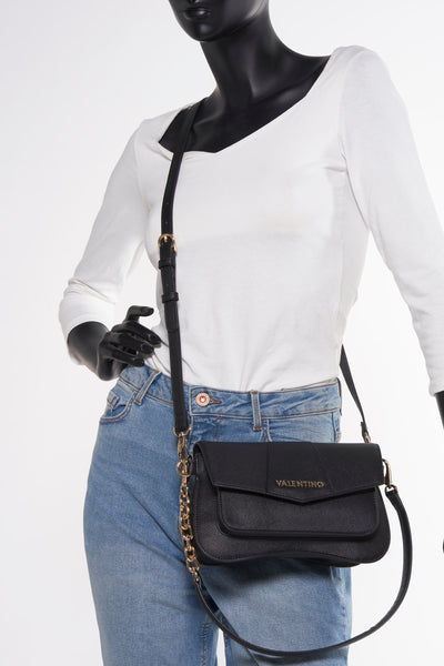 Sac à bandoulière noir de VALENTINO BAGS, avec une bandoulière réglable, porté avec un jean et un haut blanc.
