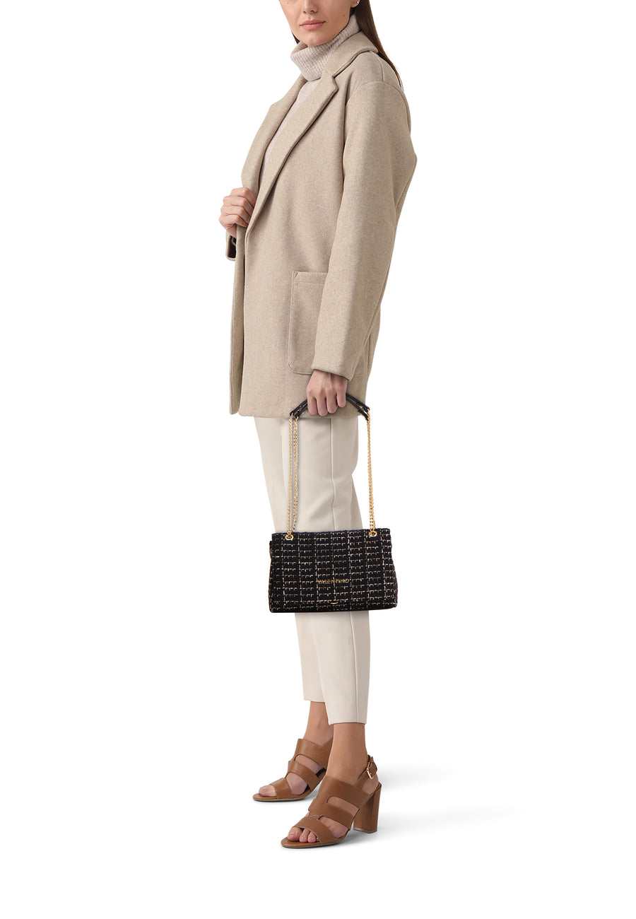 Zwarte schoudertas van VALENTINO BAGS, met ruitpatroon, gedragen met een beige jas en bruine schoenen.