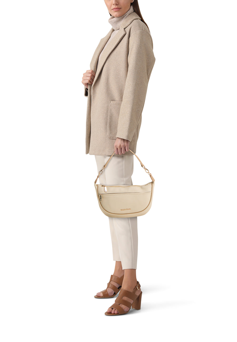 Ecru schoudertas van VALENTINO BAGS, met ritssluiting en voorvak, gedragen met een beige jas en bruine hakken.