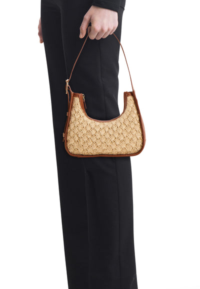 Cognac leather-trimmed crossbody bag with woven raffia body, side view on model wearing black pants