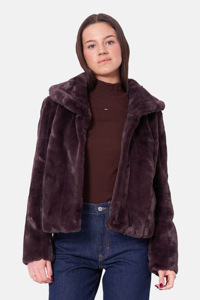 Korte bruine fauxbontjas van Guess, gedragen over een bruine coltrui en een blauwe jeans.