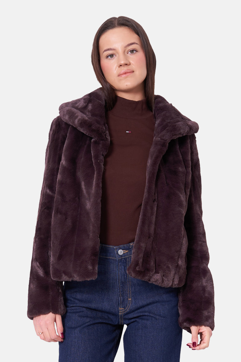 Korte bruine fauxbontjas van Guess, gedragen over een bruine coltrui en een blauwe jeans.
