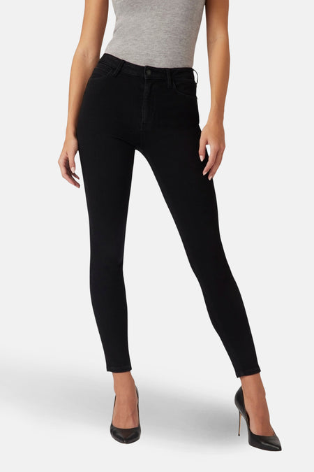Zwarte skinny jeans van Guess, met achterzakken en driehoekig logo, gedragen met een grijze top en zwarte naaldhakken.