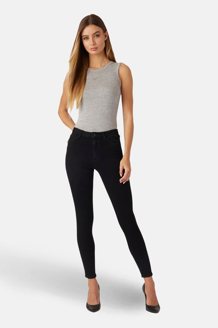 Zwarte skinny jeans van Guess, gedragen met een grijze mouwloze top en zwarte pumps.