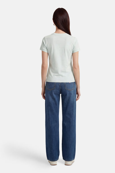 T-shirt vert à manches courtes de Guess, porté avec un jean ample orné de détails cloutés.
