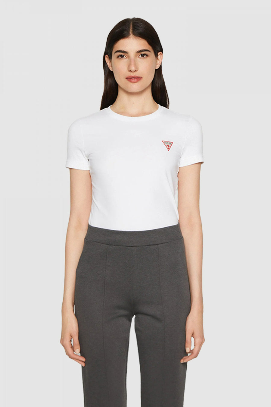 T-shirt blanc de Guess, porté avec un pantalon gris en maille lisse.
