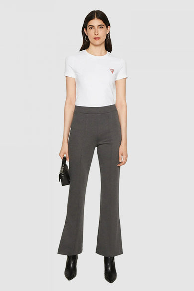 T-shirt blanc uni à manches courtes de Guess, porté avec un pantalon gris évasé, et des bottines noires pointues.