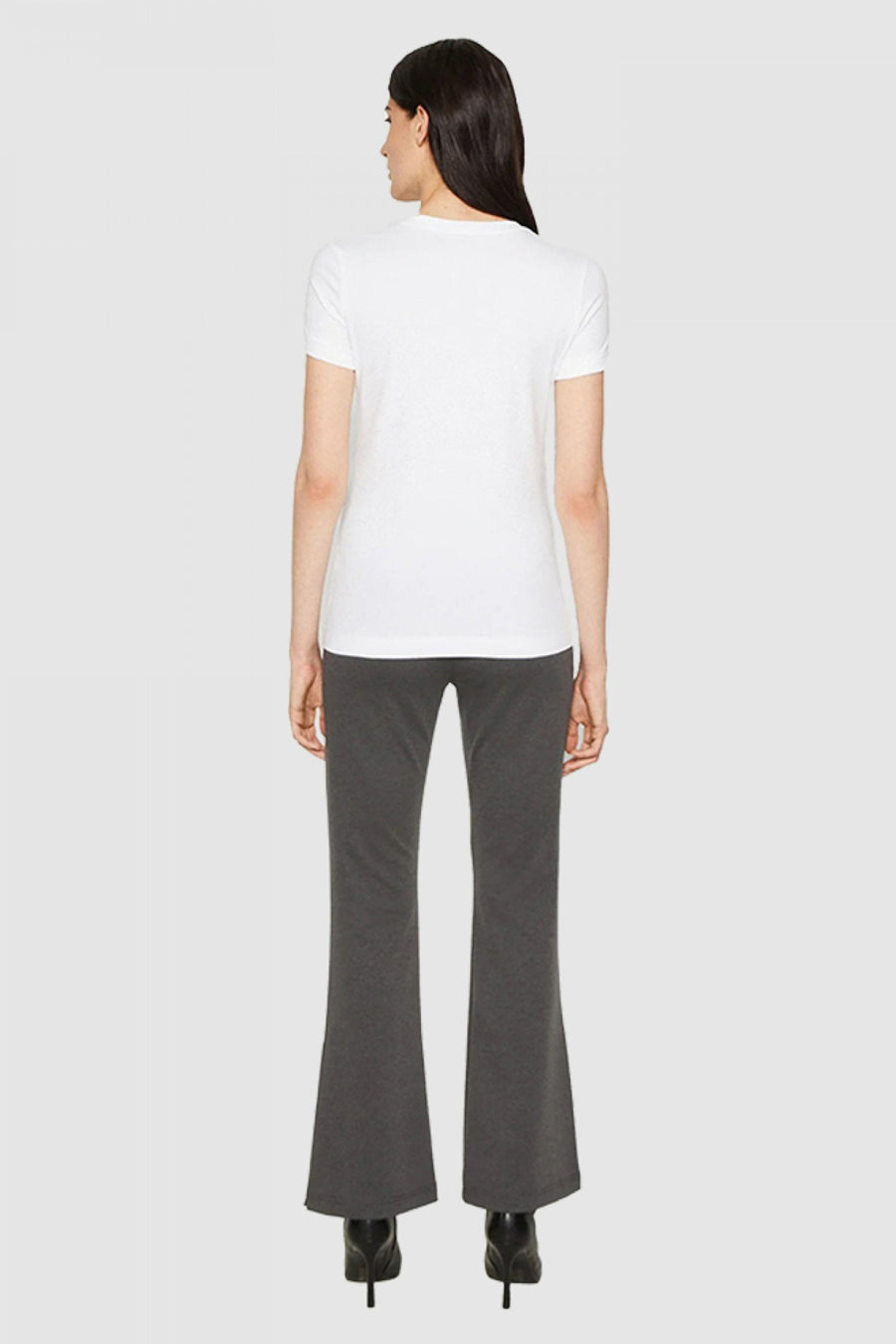 T-shirt blanc de Guess, porté avec un pantalon évasé gris foncé et des escarpins noirs.