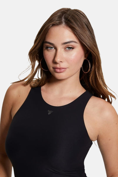 Body noir de Guess, avec un petit logo triangulaire brillant sur le devant, porté avec des boucles d'oreilles créoles dorées.