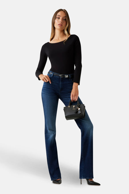 Donkerblauwe rechte jeans van Guess, gedragen met een zwarte top met lange mouwen en een zwarte tas.