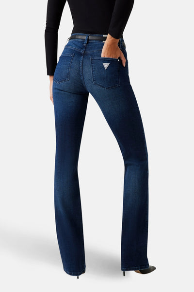Jean droit en denim bleu foncé de Guess, avec poches arrière et porté avec un haut noir.