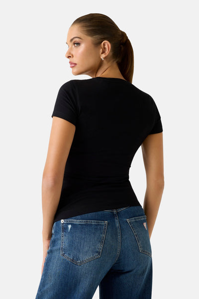 Top uni manches courtes noir de Guess, porté avec un jean bleu taille haute.