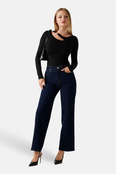 T-shirt noir à manches longues de Guess, porté avec un sac à main noir et un jean bleu foncé.
