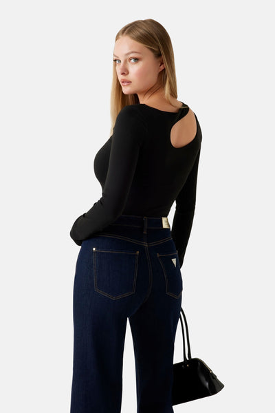 T-shirt noir à manches longues de Guess, avec découpe originale au dos, porté avec un jean bleu foncé.

