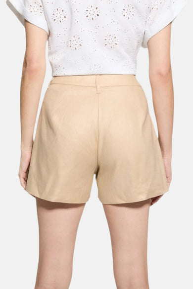 Korte beige short van Guess, van achteren gezien, gedragen met een witte geborduurde top.