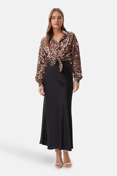 Beige blouse met lange mouwen van Guess, luipaardprint gestrikt op een lange zwarte rok.