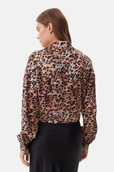 Chemisier à manches longues beige par Guess® avec imprimé léopard sur fond blanc.