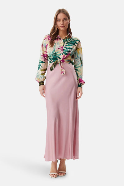 Chemisier à manches longues multicolore par Guess, à motif tropical noué sur une jupe rose longue.
