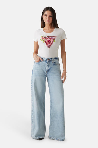 Wit T-shirt met korte mouwen van Guess, met bloemig driehoekig logo op de voorkant, gedragen met een wijde jeans.