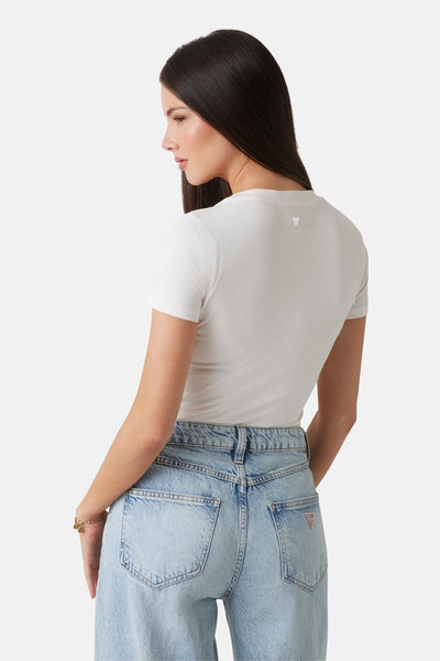Wit T-shirt met korte mouwen van Guess, met een driehoekig logo op de rug, gedragen met een high-waisted jeans.