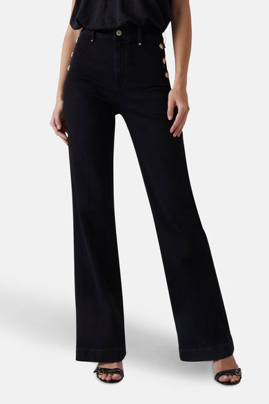 Jean évasé en denim noir de Guess, avec boutons dorés sur la taille et ourlets marqués.