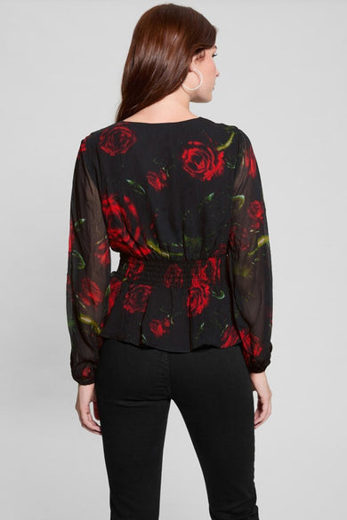 Blouse noire à manches longues de Guess, imprimé floral rouge, taille froncée, portée avec un jean noir.