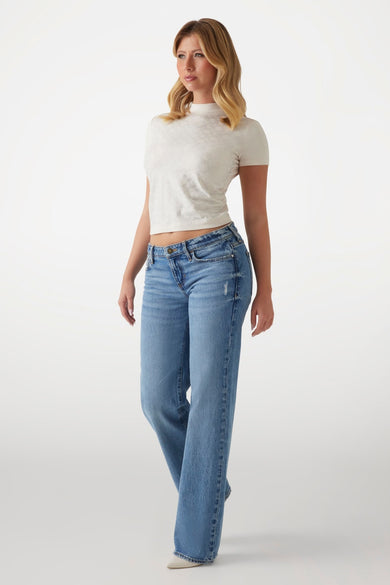 T-shirt écru à manches courtes de Guess, avec motif texturé, porté avec un jean bleu.
