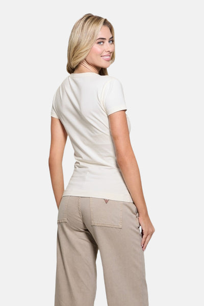 T-shirt à manches courtes blanc de Guess, porté avec un pantalon ample beige, vue de dos.
