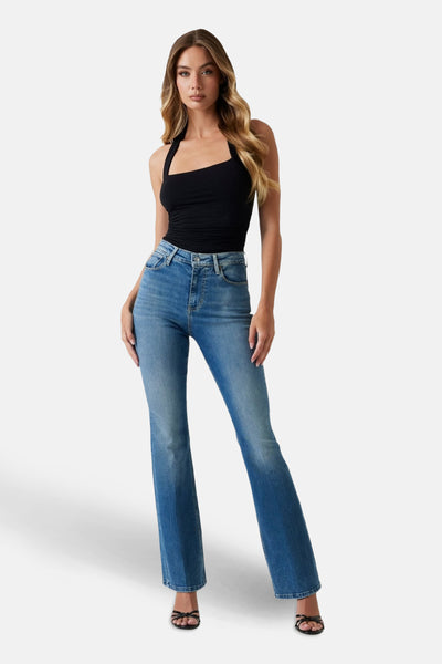 Middelblauwe uitlopende jeans van Guess, gedragen met een nauwsluitend zwart topje en sandalen met hak.