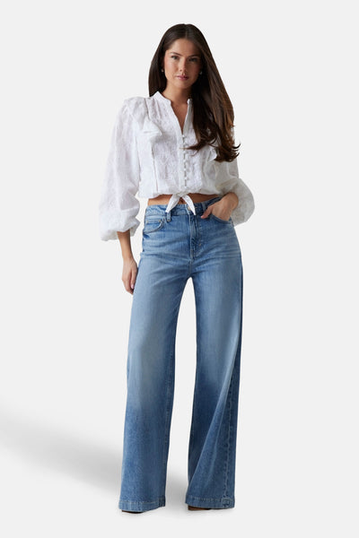 Middelblauwe wijde jeans van Guess®, gedragen met een witte getextureerde blouse.
