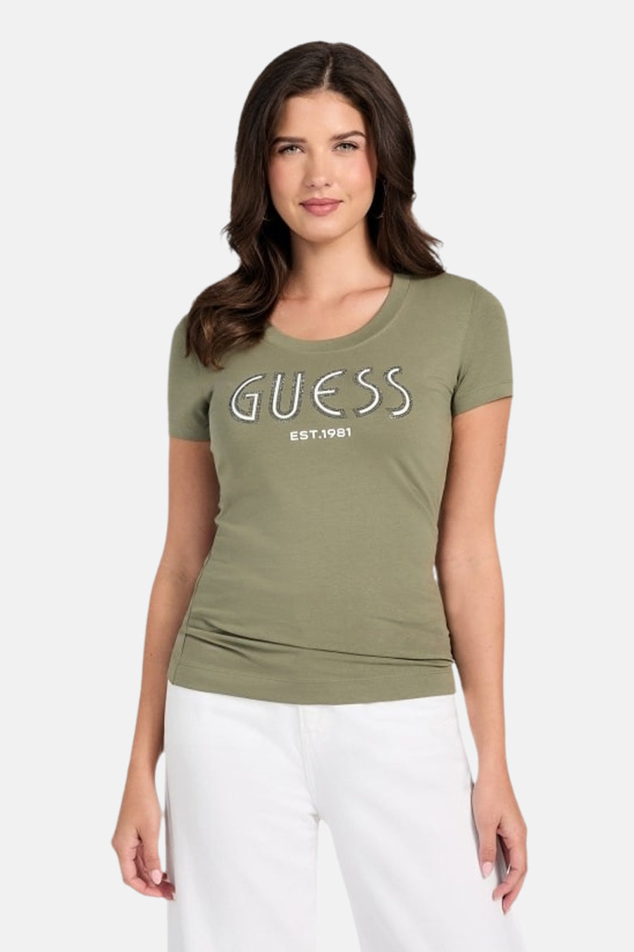 T-shirt kaki à manches courtes de Guess, avec le logo de la marque sur le devant, porté avec un pantalon blanc.
