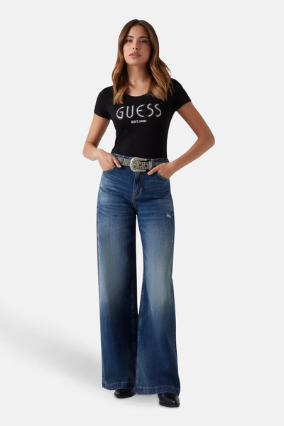T-shirt noir à manches courtes de Guess, porté avec un jean bleu taille haute et une ceinture à strass.
