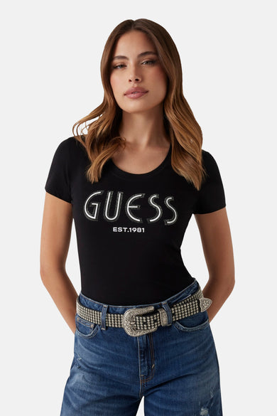 T-shirt noir à manches courtes de Guess, avec inscription blanche et ceinture à strass visible.
