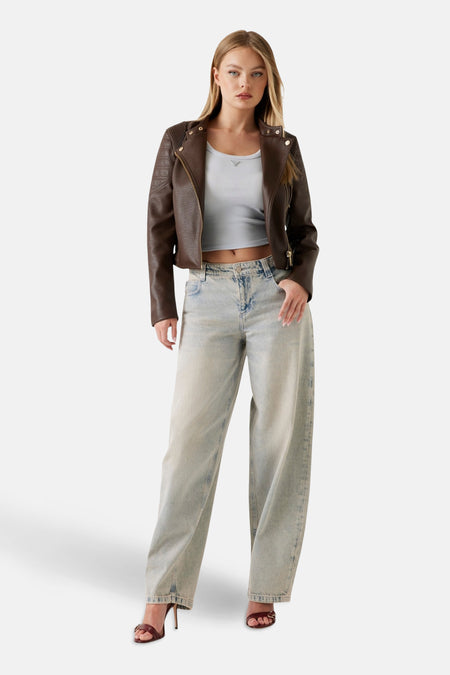 Bruin imitatielederen jas van Guess, met een gouden ritssluiting, gedragen met een top en een wijde jeans.