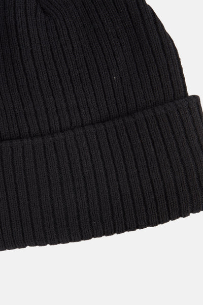 Bonnet noir en maille côtelée de DODI, texture douce et chaude, sur fond clair.