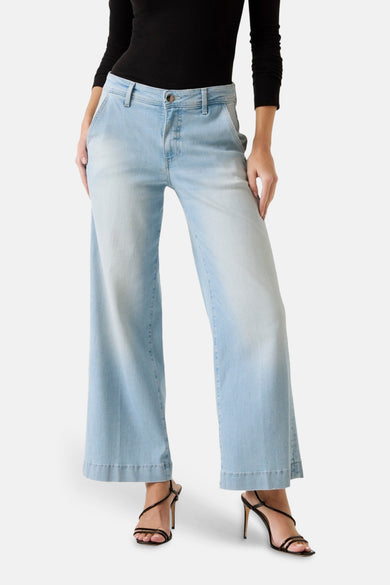 7/8 spijkerbroek in lichtblauw denim van Guess, losse pasvorm, gedragen met een zwarte top en zwarte sandalen met hak.